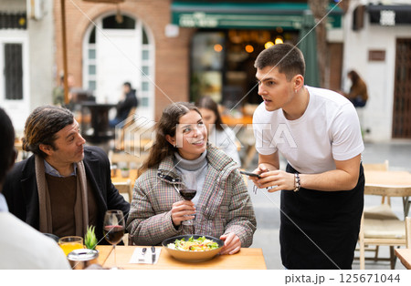 Couple husband and wife ordering from boyfriend waiter in restaurant Couple husband and wife ordering from boyfriend waiter in restaurant 125671044
