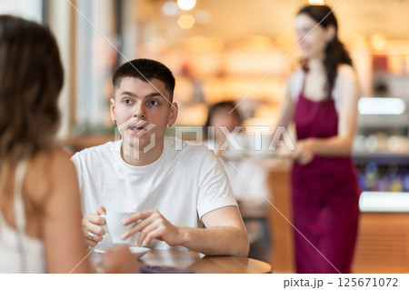 Guy in cafe sits opposite female companion, has nice conversation 125671072