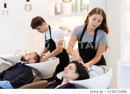 Young female hairdresser washing hair of female client 125671096