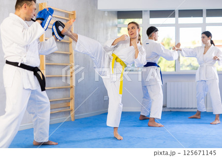 arate trainer helps woman learn how to kick during karate training arate trainer helps woman learn how to kick during karate training 125671145