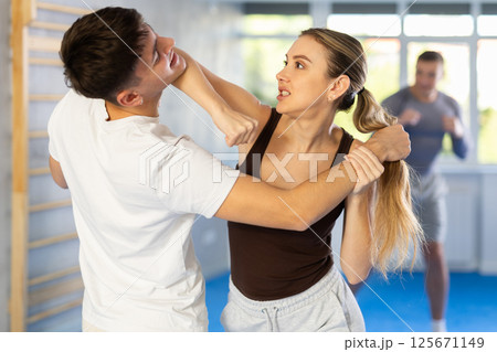 Young woman and guy training self-defense techniques Young woman and guy training self-defense techniques 125671149