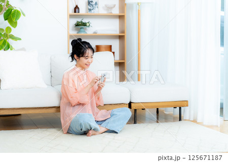 部屋でスマホを操作する若い女性 部屋でスマホを操作する若い女性 125671187