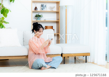 部屋でスマホを操作する若い女性 部屋でスマホを操作する若い女性 125671188