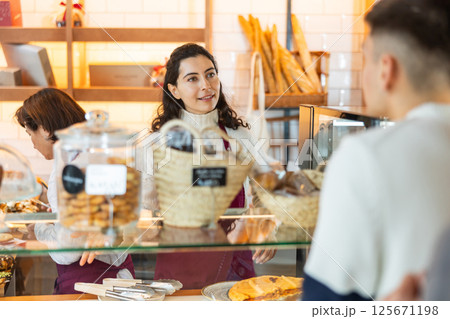 Young woman giving pastry to customer in cafe Young woman giving pastry to customer in cafe 125671198