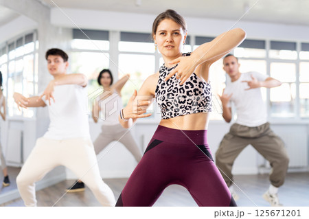 Girl enjoys active dancing, learns new movements, moves synchronously with participants of lesson Girl enjoys active dancing, learns new movements, moves synchronously with participants of lesson 125671201