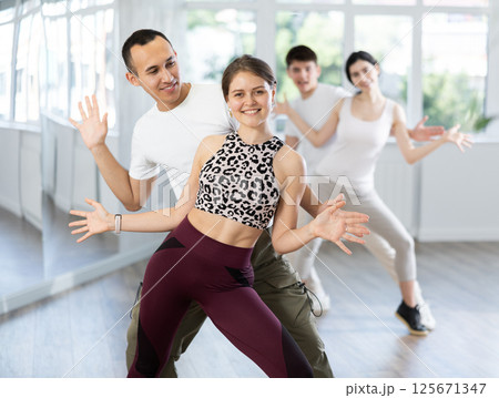 Cheerful young couple practicing playful Charleston in dance studio Cheerful young couple practicing playful Charleston in dance studio 125671347
