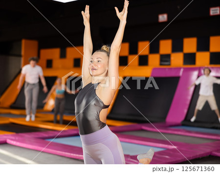 Energized European female in active wear posing on trampolines during active weekend free time in sports center 125671360