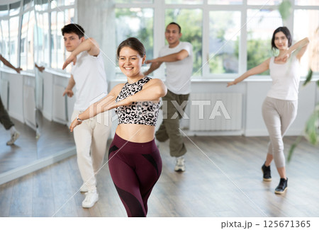Smiling girl enjoying vigorous dance at group class Smiling girl enjoying vigorous dance at group class 125671365
