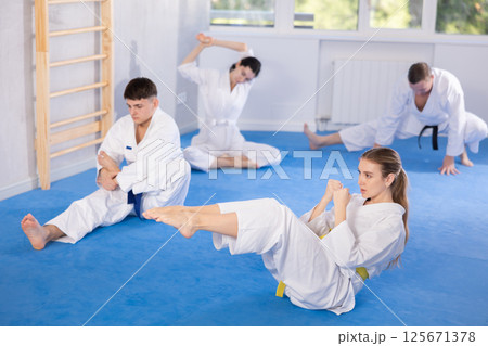 Sports team doing muscle stretching before karate or judo training 125671378