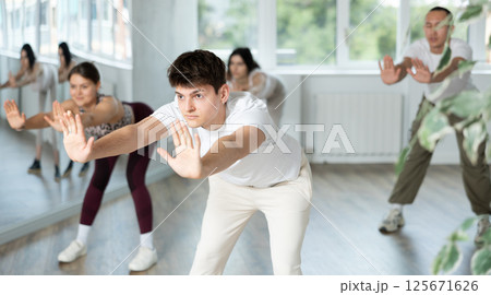 Hispanic guy performing stretching exercises before dance class 125671626