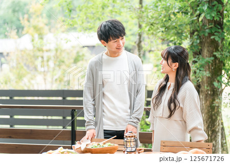 ウッドデッキ・テラス席・バルコニー席で食事するカップル・夫婦（グランピング・ベランピング） 125671726