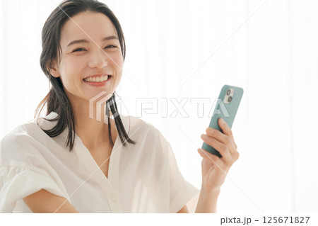 自宅でスマホを操作する30代女性 125671827