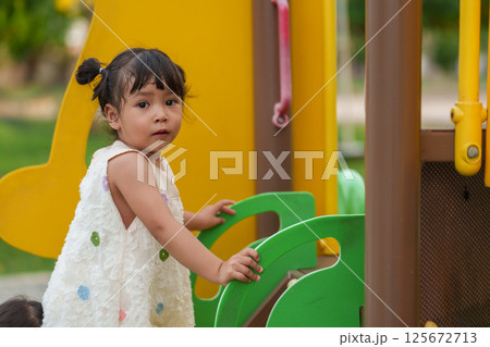happy toddler girl playing at a outdoor playground in park happy toddler girl playing at a outdoor playground in park 125672713