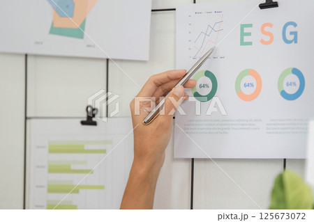 ESG analysis featuring hand pointing at sustainable metrics on wall ESG analysis featuring hand pointing at sustainable metrics on wall 125673072