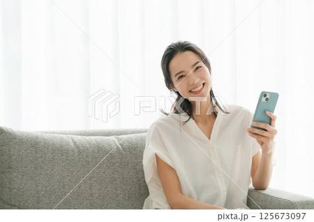 ソファでスマホを操作する女性 125673097