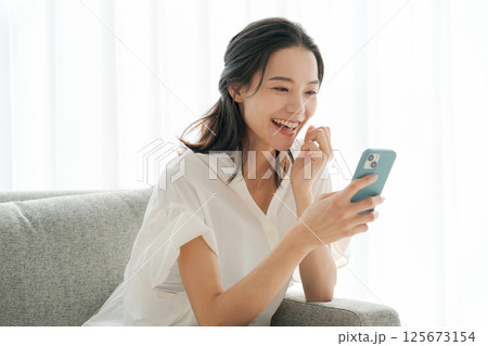 ソファでスマホを操作する女性 125673154