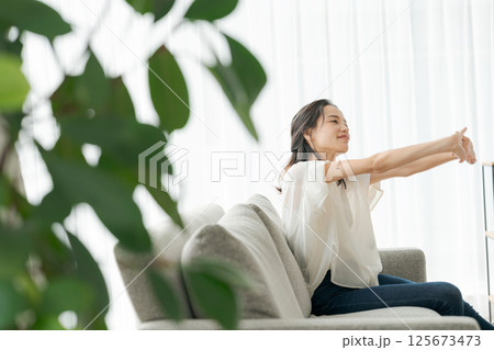 自宅でスマホを操作する30代女性 125673473