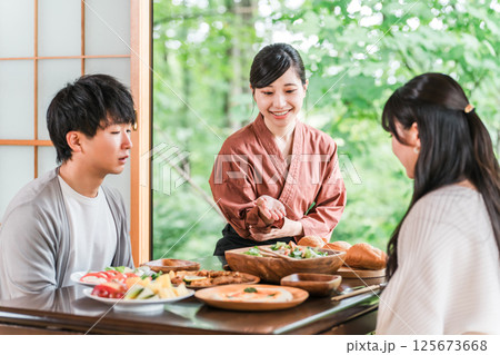 温泉旅館の客室で料理の説明をする旅館スタッフ・仲居さんの女性 温泉旅館の客室で料理の説明をする旅館スタッフ・仲居さんの女性 125673668