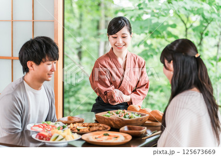 温泉旅館の客室で料理の説明をする旅館スタッフ・仲居さんの女性 温泉旅館の客室で料理の説明をする旅館スタッフ・仲居さんの女性 125673669