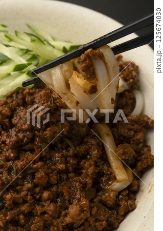 肉味噌うどんを箸で持ち上げる 125674030