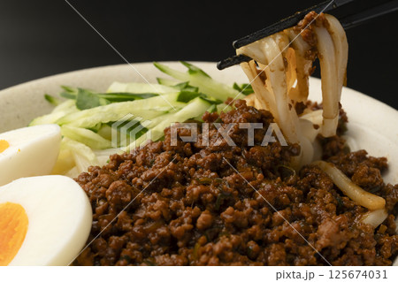 肉味噌うどんを箸で持ち上げる 125674031