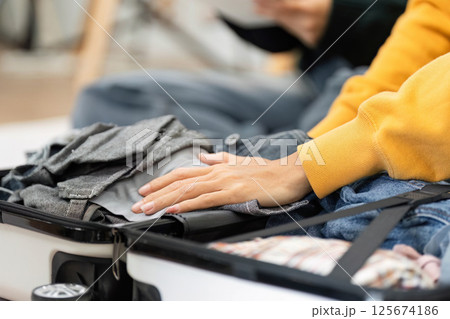 Packing organized clothes into a suitcase during travel prep 125674186
