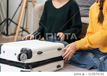 Packing a suitcase together with a friend for upcoming travel 125674192