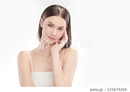 A beautiful young woman with clean, fresh skin against a white background. Skincare, facial treatment, cosmetology, beauty, and spa. An elegant portrait of an woman. 125674204
