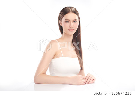 A beautiful young woman with clean, fresh skin against a white background. Skincare, facial treatment, cosmetology, beauty, and spa. An elegant portrait of an woman. 125674219