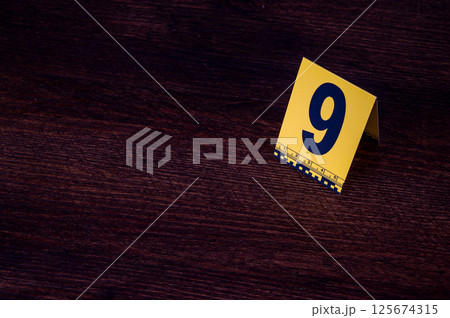 Yellow crime scene evidence marker number 9 on the floor in the room. High quality photo Yellow crime scene evidence marker number 9 on the floor in the room. High quality photo 125674315