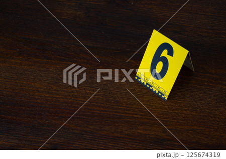 Yellow crime scene evidence marker number 6 on the floor in the room. High quality photo 125674319