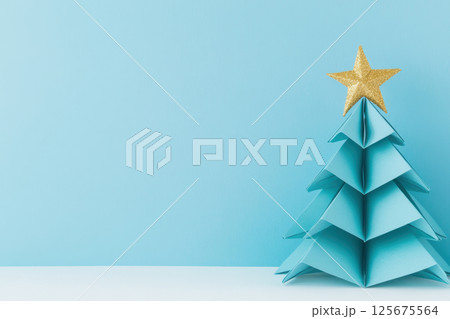 Minimalist origami christmas tree with golden star on light blue background celebrating festive season and creative design, AI Generative 125675564