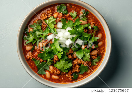 Hearty bowl of chili with ground meat, beans, and fresh cilantro garnish on a light background, AI Generative 125675697