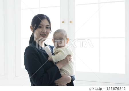 赤ちゃんを抱くワーキングマザー 125676842