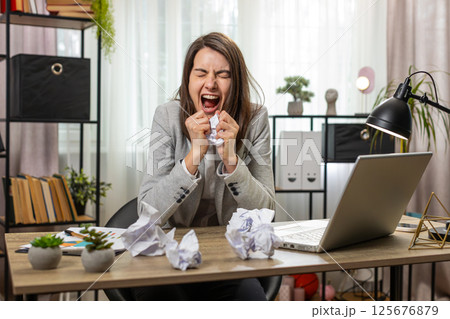 Angry furious business woman working at office throwing crumpled paper having nervous breakdown Angry furious business woman working at office throwing crumpled paper having nervous breakdown 125676879
