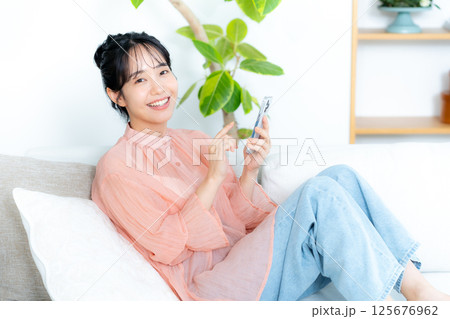 リビングでくつろぐ若い女性 リビングでくつろぐ若い女性 125676962