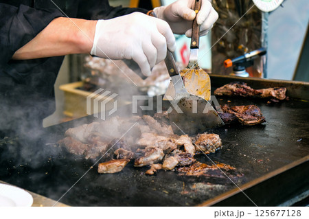 Chef cooking beef steak on a hot pan in a restaurant kitchen 125677128