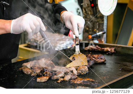 Chef cooking beef steak on a hot pan in a restaurant kitchen Chef cooking beef steak on a hot pan in a restaurant kitchen 125677129