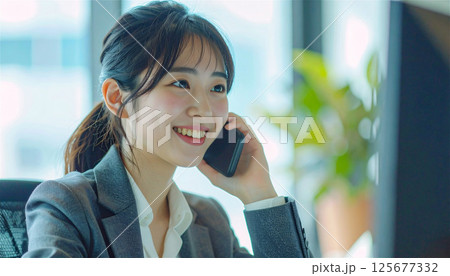 電話応対をする笑顔の若いビジネスウーマン・オフィスの明るい日差しの中で 電話応対をする笑顔の若いビジネスウーマン・オフィスの明るい日差しの中で 125677332