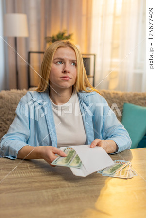 Young woman sorts money cash separating portions planning financial obligations, future expenses Young woman sorts money cash separating portions planning financial obligations, future expenses 125677409