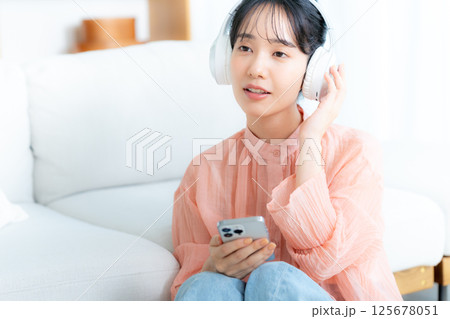 部屋で音楽を聴く若い女性 125678051
