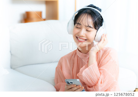 部屋で音楽を聴く若い女性 部屋で音楽を聴く若い女性 125678052