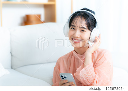 部屋で音楽を聴く若い女性 125678054