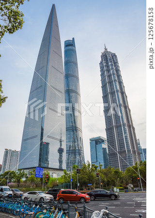 Shanghai, China - 1 April 2025: Shanghai Tower, Jinmao Tower and SWFC pierce the twilight sky as evening traffic flows below, with parked bicycles adding urban charm to this spring sunset scene in Shanghai, China - 1 April 2025: Shanghai Tower, Jinmao Tower and SWFC pierce the twilight sky as evening traffic flows below, with parked bicycles adding urban charm to this spring sunset scene in 125678158