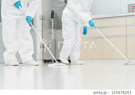 防塵服,クリーンウェアをを着て除菌清掃する清掃業,特殊清掃業の男女の足元（衛生管理,クリーンリーム） 125678261
