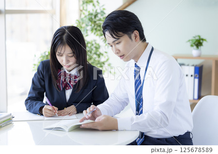 塾で勉強する高校生と講師 125678589
