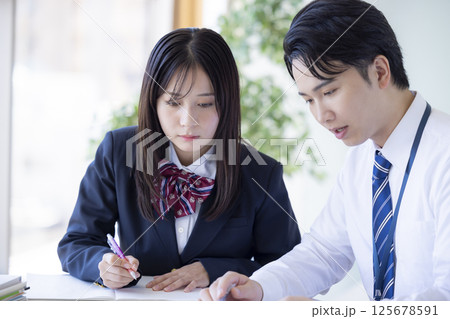 塾で勉強する高校生と講師 125678591