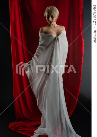 Elegant woman poses gracefully with flowing cloth in studio setting 125679963