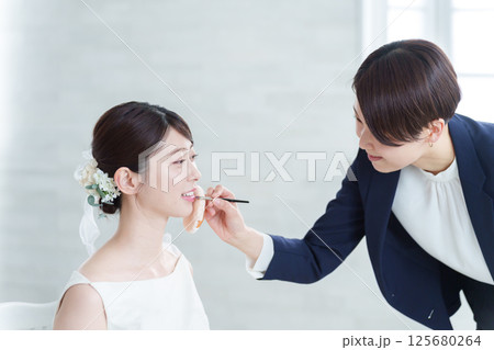結婚式場のヘアメイクと新婦 結婚式場のヘアメイクと新婦 125680264