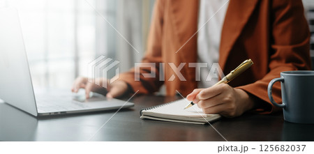 View of young professional businessman writing his idea concepts on notebook while working on his project 125682037